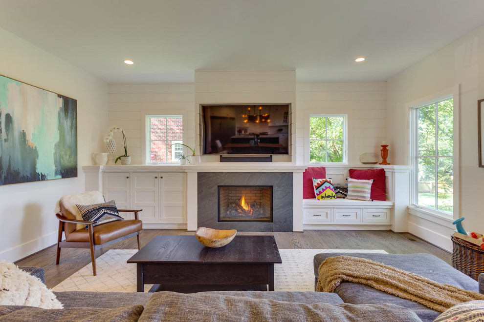Photo of a large transitional open concept living room in DC Metro with white walls, medium hardwood floors, a standard fireplace, a wall-mounted tv and a tile fireplace surround.