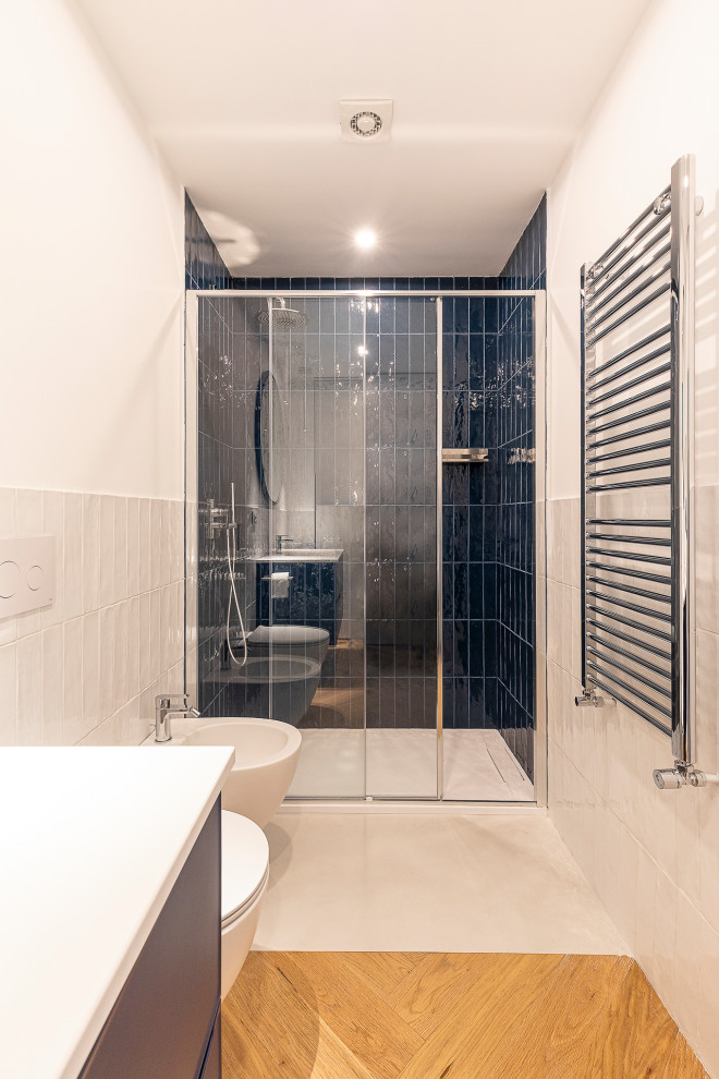 Свежая идея для дизайна: маленькая главная ванная комната в стиле модернизм с плоскими фасадами, синими фасадами, ванной на ножках, душем в нише, раздельным унитазом, белой плиткой, керамической плиткой, белыми стенами, светлым паркетным полом, консольной раковиной, столешницей из известняка, бежевым полом, душем с раздвижными дверями, белой столешницей, тумбой под одну раковину, подвесной тумбой и кессонным потолком для на участке и в саду - отличное фото интерьера
