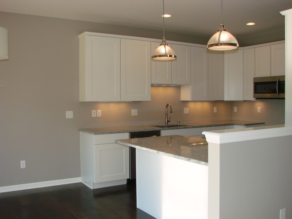 Kitchen - transitional dark wood floor kitchen idea with a double-bowl sink, shaker cabinets, white cabinets, granite countertops and stainless steel appliances