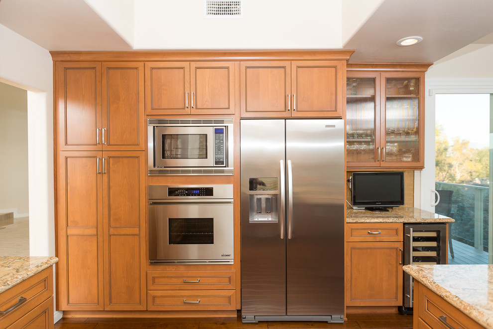 Inspiration for a large transitional u-shaped dark wood floor eat-in kitchen remodel in Orange County with a single-bowl sink, raised-panel cabinets, medium tone wood cabinets, granite countertops, beige backsplash, ceramic backsplash, stainless steel appliances and no island