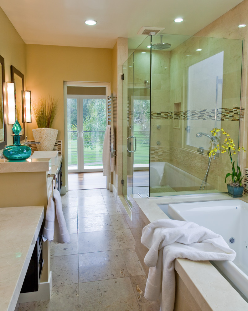 Inspiration for a mid-sized modern bathroom in San Diego with shaker cabinets, dark wood cabinets, a drop-in tub, a corner shower, beige tile, limestone, beige walls, limestone floors, a vessel sink, limestone benchtops, beige floor and a hinged shower door.