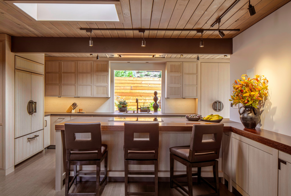 Photo of a mid-sized midcentury galley eat-in kitchen in San Francisco with an undermount sink, recessed-panel cabinets, light wood cabinets, concrete benchtops, beige splashback, panelled appliances, dark hardwood floors, a peninsula, brown floor, brown benchtop and exposed beam.
