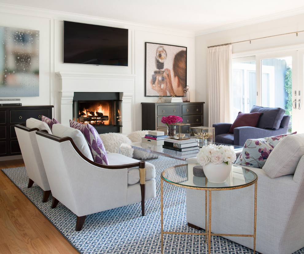 Mid-sized transitional formal enclosed living room in San Francisco with white walls, medium hardwood floors, a standard fireplace, a plaster fireplace surround, a wall-mounted tv and beige floor.