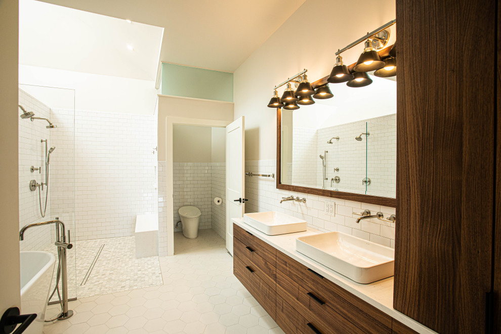 Photo of a large contemporary master wet room bathroom in Milwaukee with flat-panel cabinets, brown cabinets, a freestanding tub, a one-piece toilet, white tile, ceramic tile, multi-coloured walls, porcelain floors, a vessel sink, engineered quartz benchtops, white floor, an open shower, white benchtops, a shower seat, a double vanity, a floating vanity and vaulted.