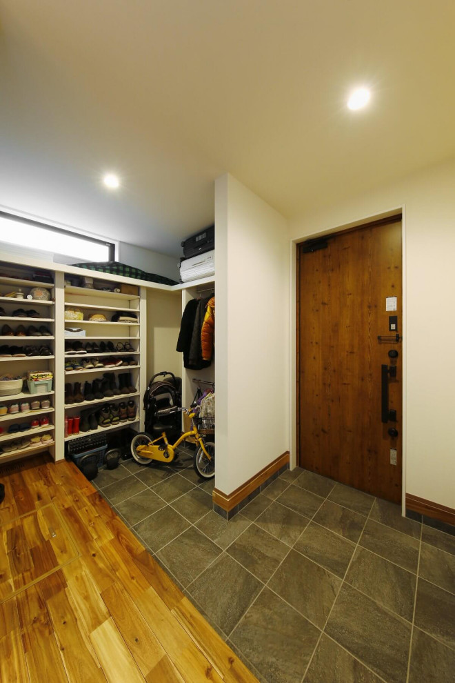 Design ideas for a mid-sized country entry hall in Tokyo Suburbs with white walls, a single front door, a dark wood front door, grey floor, wallpaper and wallpaper.