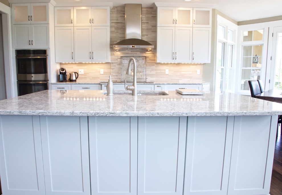 Example of a mid-sized transitional galley eat-in kitchen design with white cabinets, granite countertops, beige backsplash, stone tile backsplash and stainless steel appliances