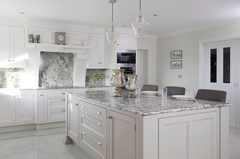 Photo of a large transitional l-shaped eat-in kitchen in Other with an undermount sink, beaded inset cabinets, white cabinets, granite benchtops, grey splashback, stone slab splashback, stainless steel appliances, porcelain floors, with island and grey floor.