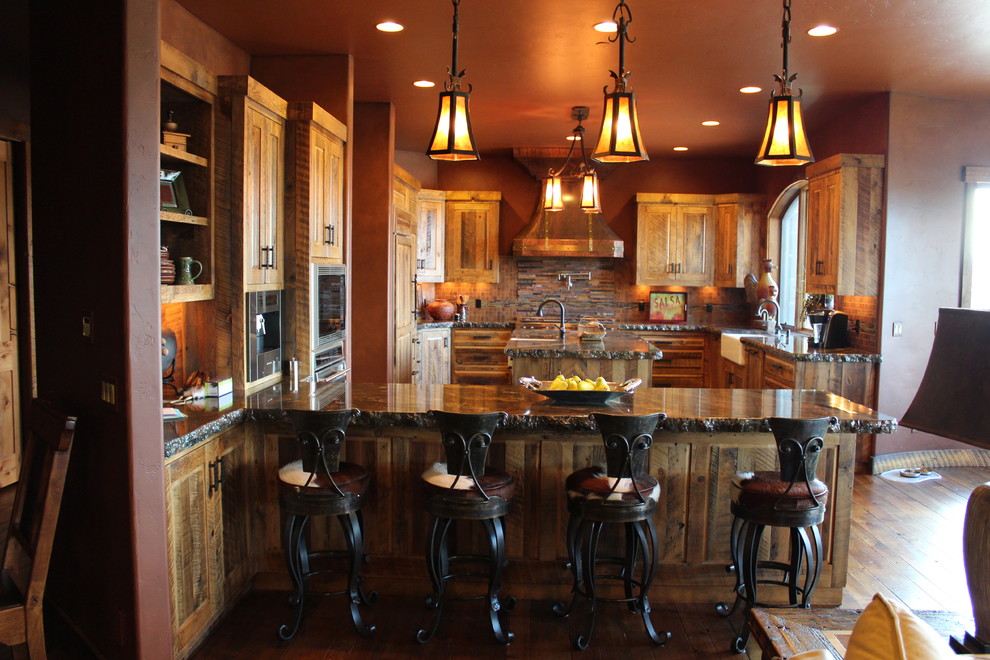 Eat-in kitchen - mid-sized rustic u-shaped medium tone wood floor eat-in kitchen idea with a farmhouse sink, raised-panel cabinets, distressed cabinets, granite countertops, multicolored backsplash, glass tile backsplash, paneled appliances and an island