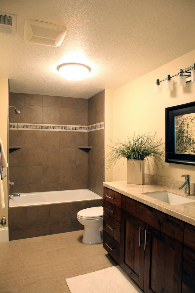 Mid-sized traditional 3/4 bathroom in Salt Lake City with an undermount sink, shaker cabinets, dark wood cabinets, engineered quartz benchtops, a drop-in tub, a shower/bathtub combo, beige tile, porcelain tile, beige walls and porcelain floors.