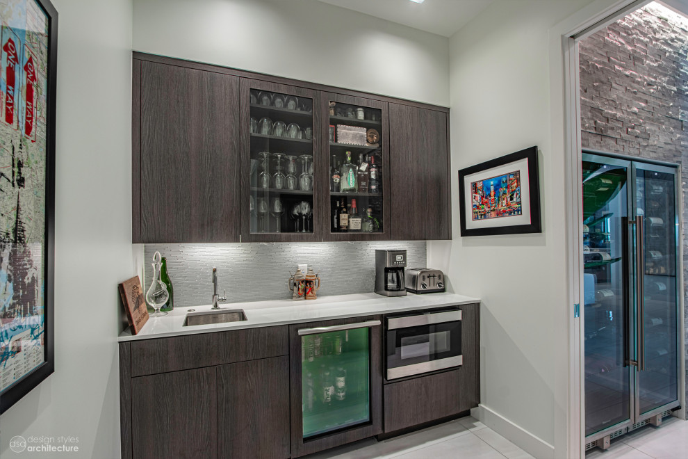 Design ideas for a small contemporary single-wall wet bar in Tampa with a drop-in sink, glass-front cabinets, dark wood cabinets, quartz benchtops, grey splashback, matchstick tile splashback, ceramic floors, white floor and white benchtop.