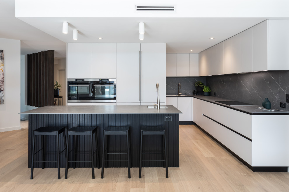 Contemporary kitchen in Perth with grey cabinets, tile benchtops, grey splashback, porcelain splashback, light hardwood floors, with island and grey benchtop.