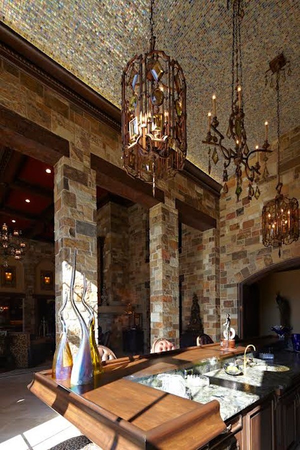 Example of a mid-sized mountain style limestone floor enclosed kitchen design in Austin with an undermount sink, recessed-panel cabinets, dark wood cabinets and an island