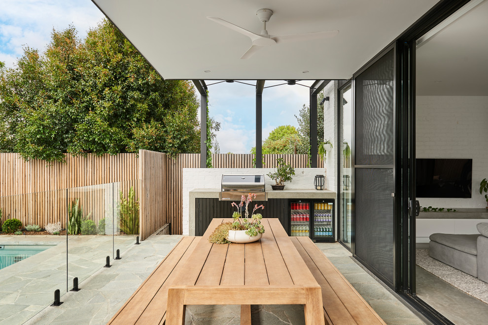 Стильный дизайн: двор среднего размера на заднем дворе в современном стиле с летней кухней, покрытием из каменной брусчатки и навесом - последний тренд