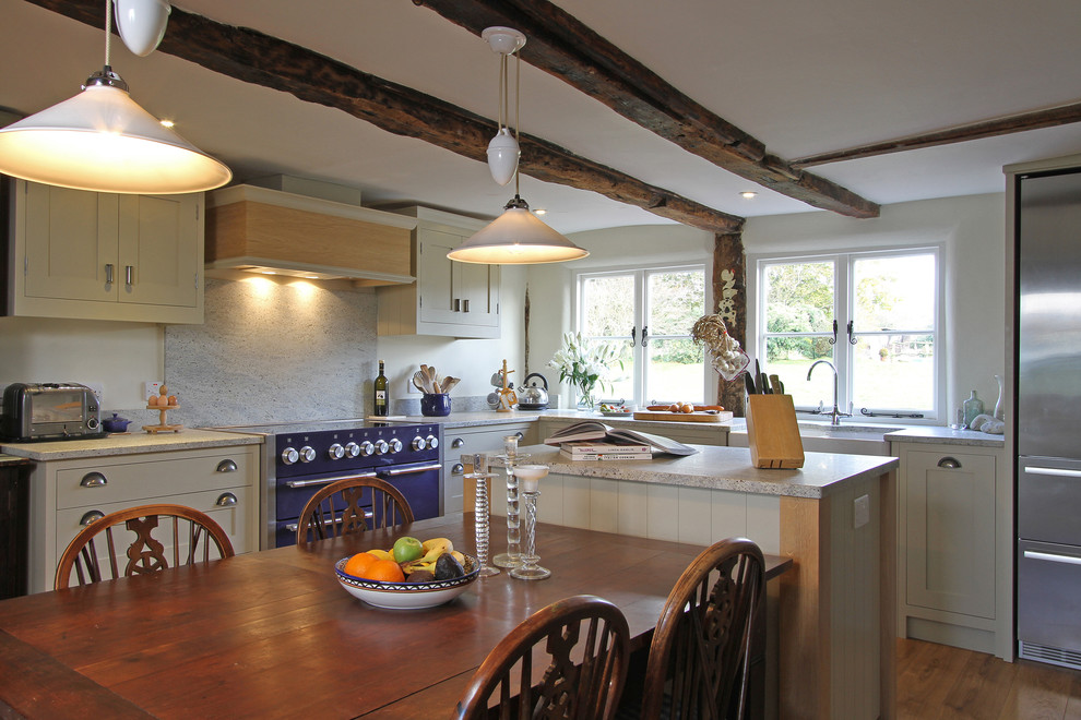 Design ideas for a large country l-shaped eat-in kitchen in Hampshire with shaker cabinets, beige cabinets, coloured appliances, granite benchtops, stone slab splashback, white splashback, a farmhouse sink, dark hardwood floors and with island.