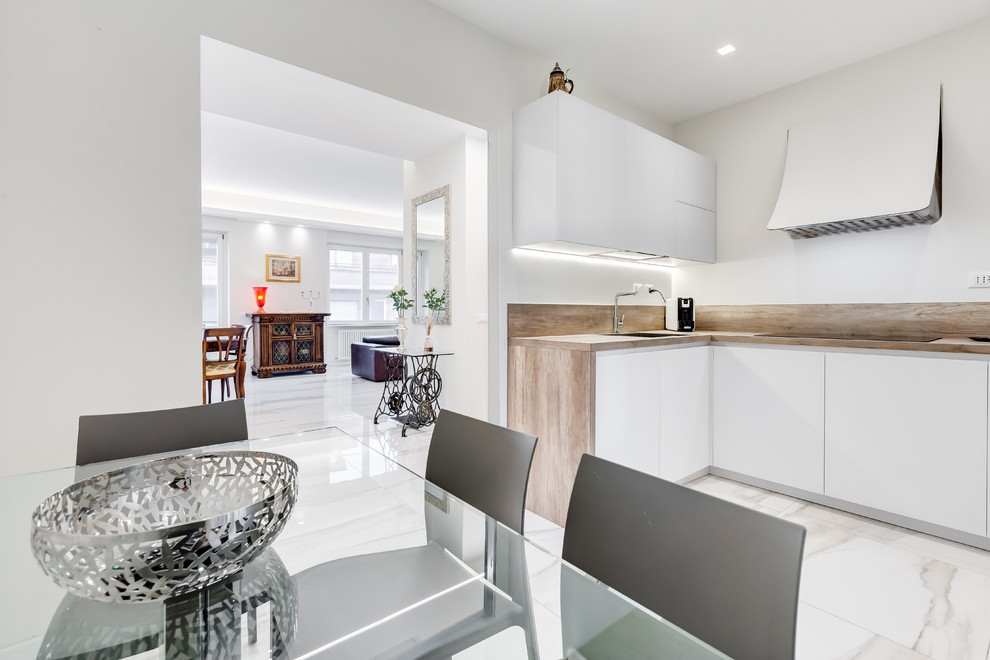 Photo of a contemporary u-shaped eat-in kitchen in Rome with an undermount sink, flat-panel cabinets, white cabinets, wood benchtops, brown splashback, timber splashback, stainless steel appliances, no island, white floor and brown benchtop.
