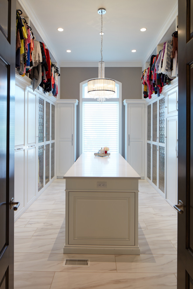 Design ideas for a large transitional gender-neutral walk-in wardrobe in Omaha with raised-panel cabinets, white cabinets, porcelain floors and white floor.