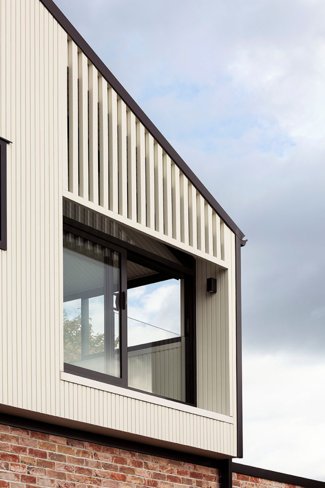 Inspiration for a Mid-sized contemporary Two-storey Brick White house exterior in Auckland With a Gable Roof, a Metal Roof, a Black Roof and Board and Batten Siding.