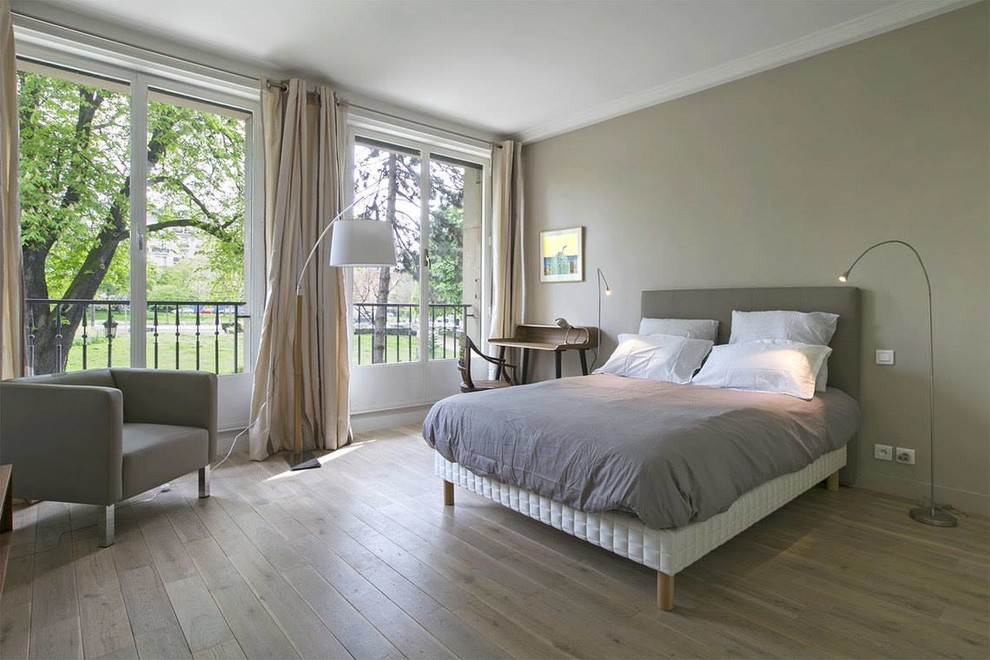 Mid-sized transitional master bedroom in Paris with light hardwood floors, grey walls and no fireplace.