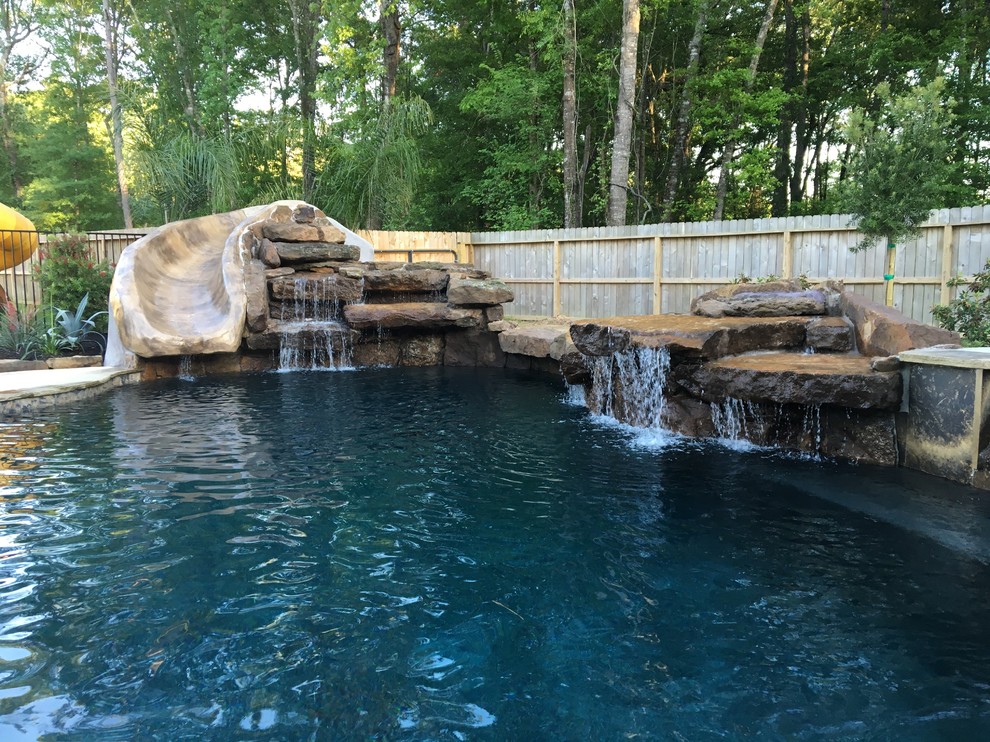 This is an example of a large country backyard custom-shaped lap pool in Houston with a water slide and natural stone pavers.