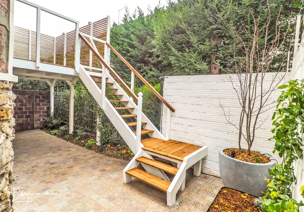 Imagen de terraza clásica de tamaño medio en patio trasero con jardín vertical, pérgola y barandilla de madera
