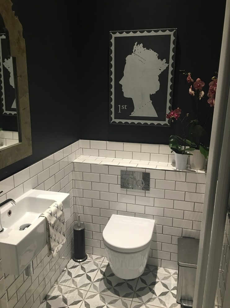 Inspiration for a small traditional powder room in London with white tile, black walls, ceramic floors, a wall-mount toilet, a wall-mount sink, subway tile and multi-coloured floor.