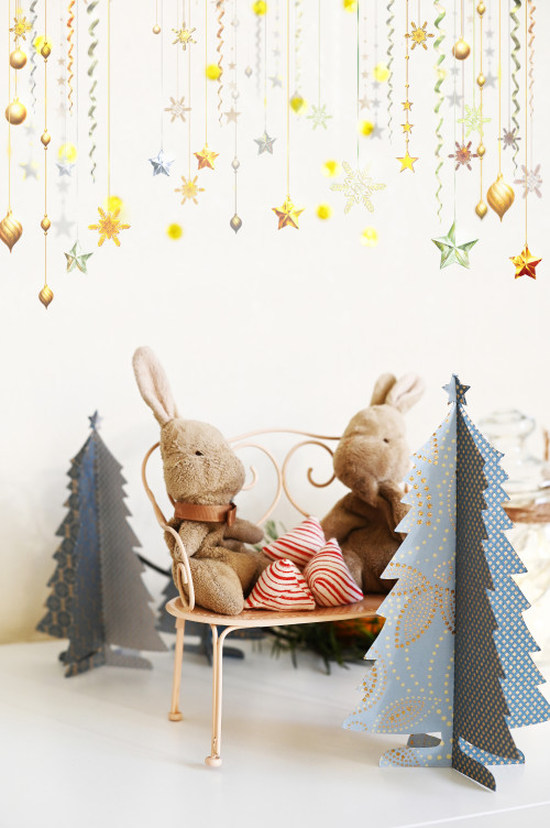 Christmas scene with fabric bunnies on a mini bench surrounded by blue paper Christmas trees.