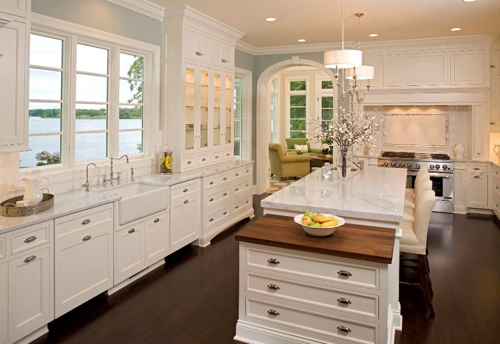 Inspiration for a large traditional kitchen in Philadelphia with a farmhouse sink, white cabinets, marble benchtops, stainless steel appliances, brown floor, recessed-panel cabinets, window splashback, dark hardwood floors and with island.
