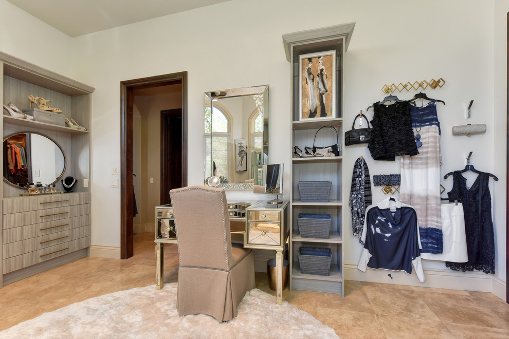 Photo of an expansive transitional women's dressing room in Sacramento with open cabinets, grey cabinets, limestone floors and beige floor.