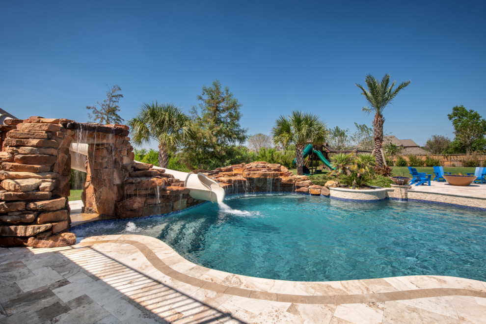 Foto de piscina con tobogán clásica grande a medida en patio trasero con adoquines de piedra natural