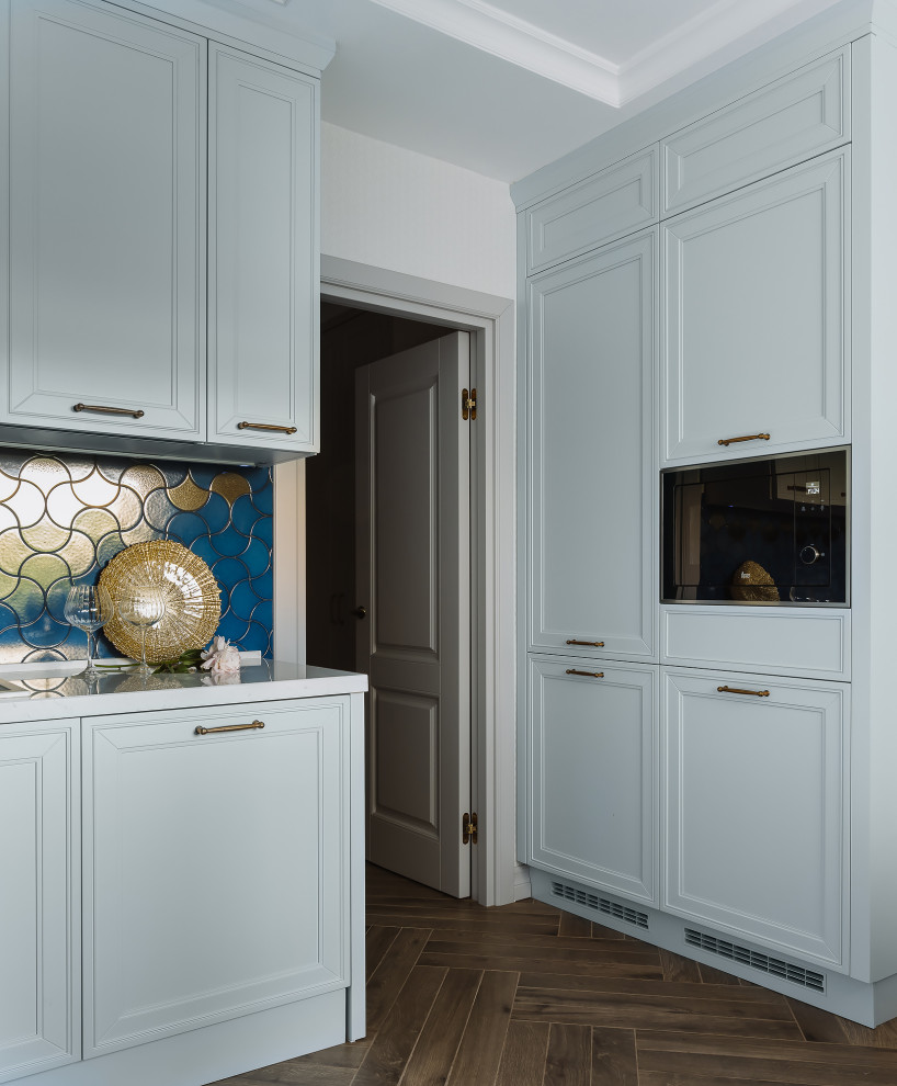 Mid-sized transitional l-shaped separate kitchen in Moscow with a drop-in sink, raised-panel cabinets, turquoise cabinets, quartz benchtops, blue splashback, ceramic splashback, black appliances, porcelain floors, brown floor and white benchtop.