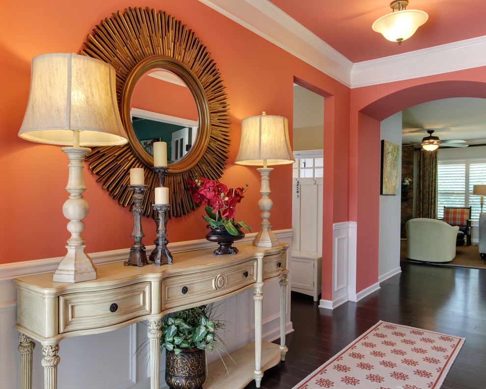Inspiration for a mid-sized eclectic entry hall in Raleigh with orange walls, dark hardwood floors and brown floor.