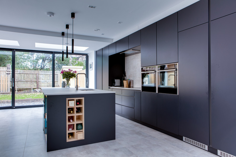 Design ideas for a mid-sized contemporary galley open plan kitchen in Dublin with a drop-in sink, flat-panel cabinets, blue cabinets, quartzite benchtops, grey splashback, stone slab splashback, stainless steel appliances, porcelain floors, with island, grey floor and grey benchtop.