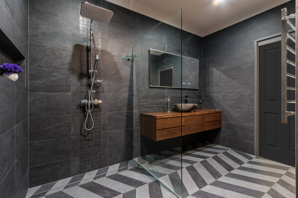Photo of a large traditional master bathroom in Brisbane with furniture-like cabinets, medium wood cabinets, a corner shower, a one-piece toilet, gray tile, ceramic tile, grey walls, ceramic floors, a vessel sink, grey floor and an open shower.