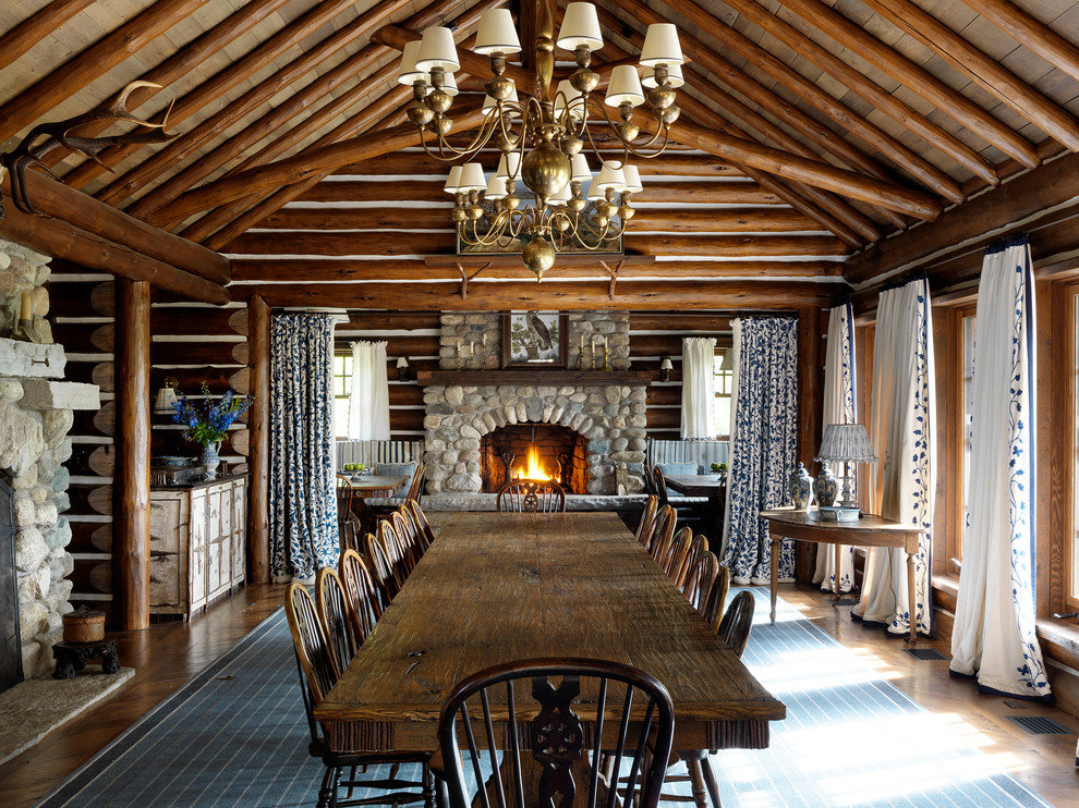 Country dining room in Other with brown walls, a standard fireplace and a stone fireplace surround.