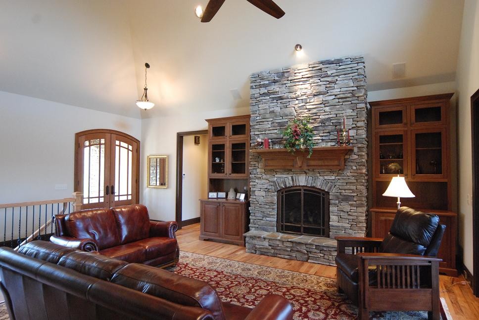 This is an example of a mid-sized traditional enclosed family room in Other with a standard fireplace, white walls, light hardwood floors, a stone fireplace surround, no tv and beige floor.