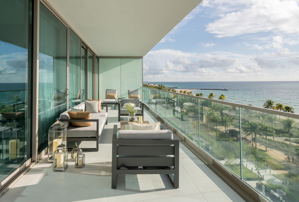 Mid-sized contemporary balcony in Miami with a roof extension and glass railing.