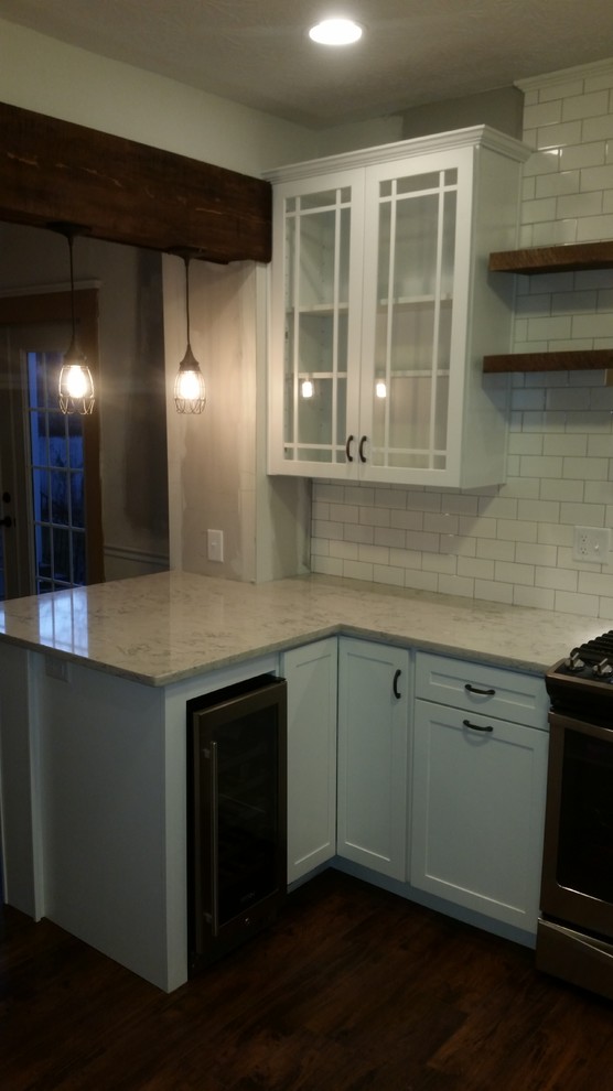Home design - mid-sized transitional u-shaped dark wood floor home design idea in Cincinnati with an undermount sink, flat-panel cabinets, white cabinets, quartz countertops, white backsplash, subway tile backsplash, stainless steel appliances and a peninsula