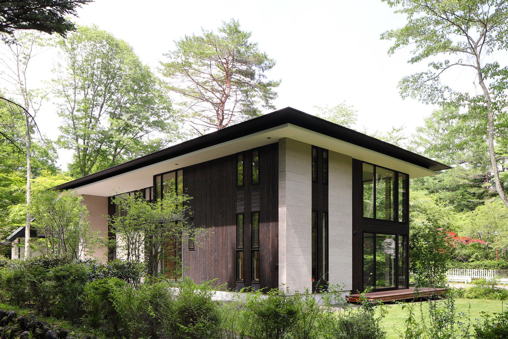 Photo of a mid-sized modern split-level black house exterior in Other with wood siding, a hip roof and a metal roof.