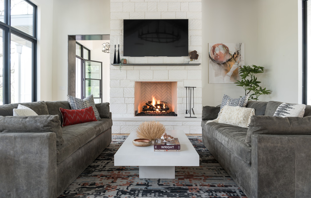 This is an example of a transitional living room in Austin with white walls, light hardwood floors, a standard fireplace, a tile fireplace surround, a wall-mounted tv and brown floor.