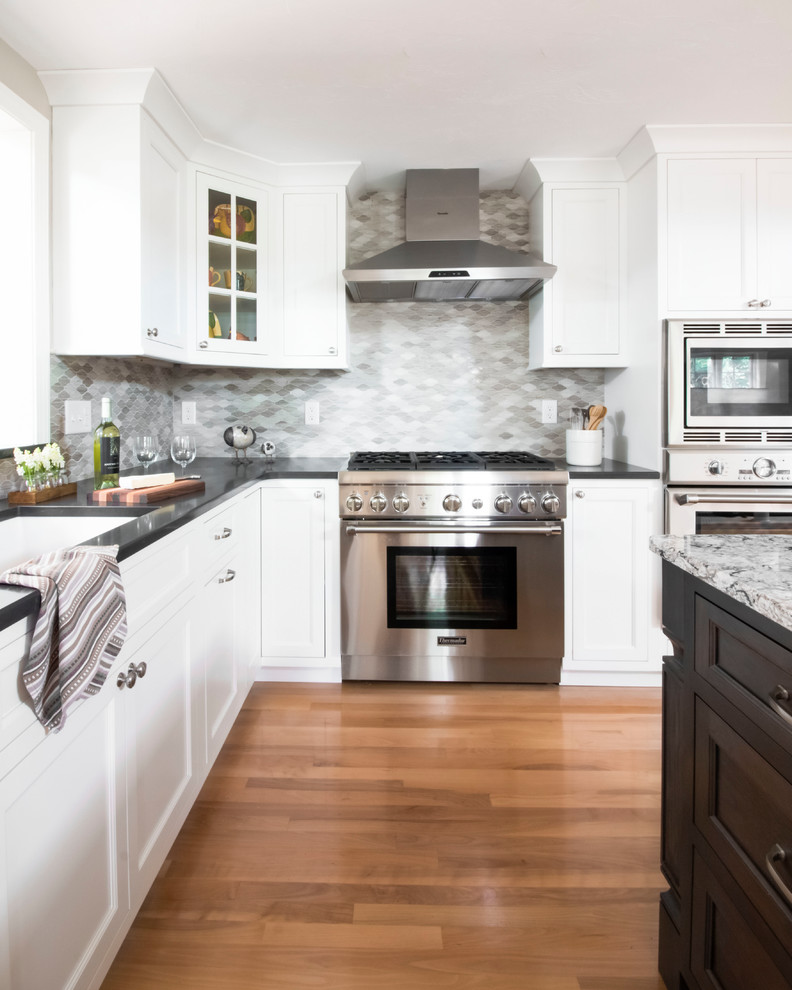 Design ideas for a mid-sized traditional l-shaped eat-in kitchen in Boston with an undermount sink, shaker cabinets, white cabinets, quartz benchtops, grey splashback, stone tile splashback, stainless steel appliances, light hardwood floors, with island and brown floor.