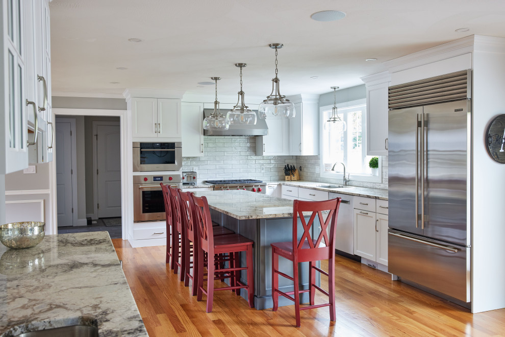 Inspiration for a transitional l-shaped medium tone wood floor eat-in kitchen remodel in Boston with an undermount sink, recessed-panel cabinets, white cabinets, granite countertops, gray backsplash, ceramic backsplash, stainless steel appliances and an island