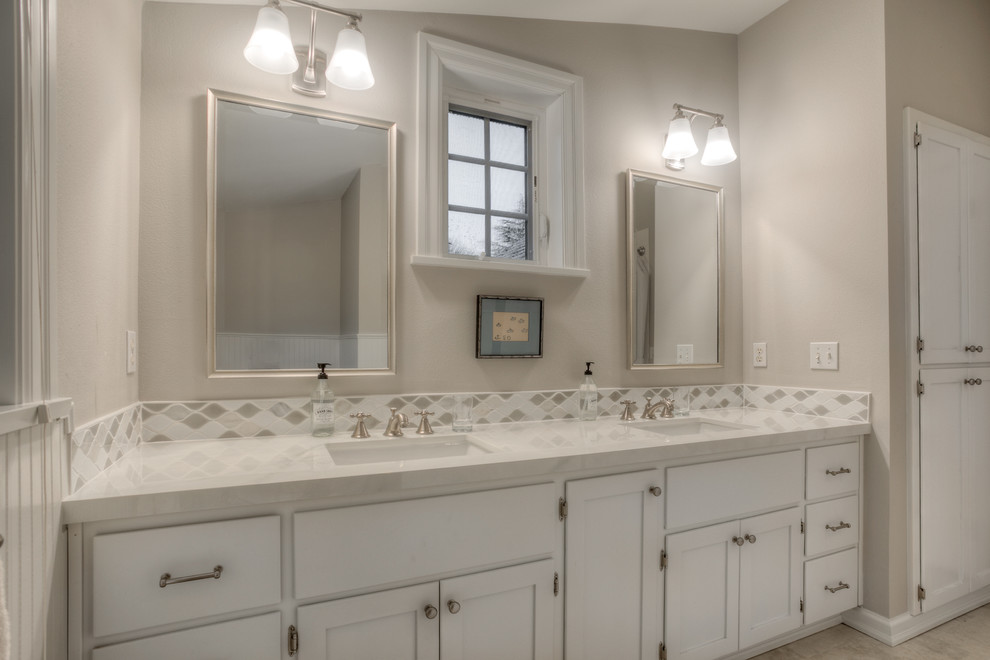 Photo of a large traditional bathroom in Seattle with recessed-panel cabinets, white cabinets, a drop-in tub, a shower/bathtub combo, a one-piece toilet, multi-coloured tile, subway tile, grey walls, porcelain floors, an undermount sink and granite benchtops.