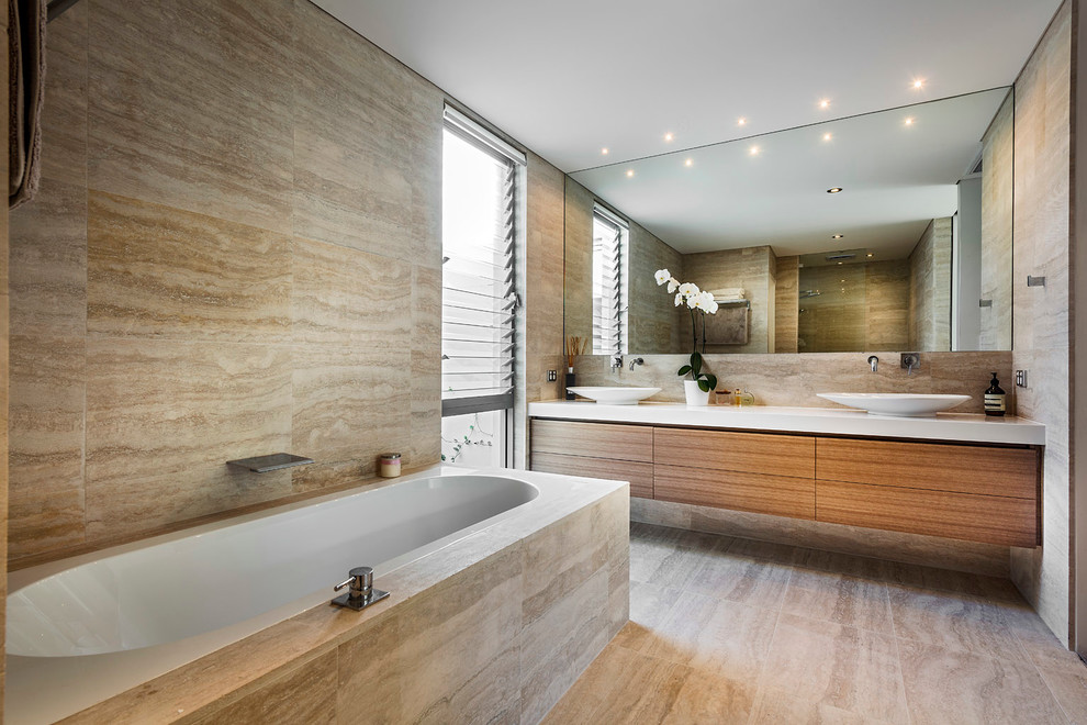 Photo of a mid-sized contemporary bathroom in Perth with a vessel sink, medium wood cabinets, a drop-in tub and travertine.