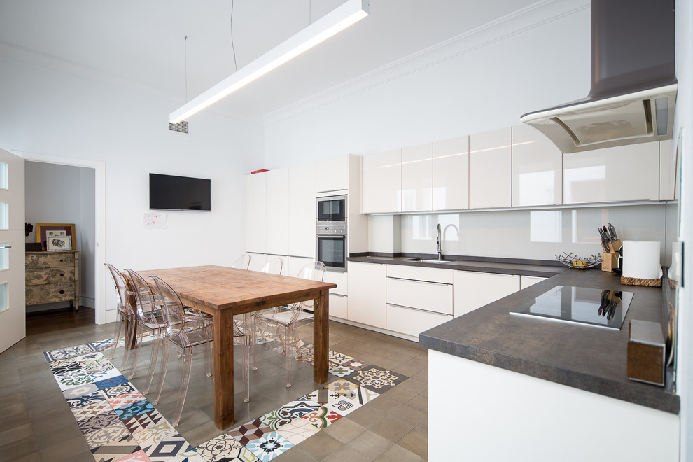 This is an example of a large contemporary l-shaped eat-in kitchen in Seville with flat-panel cabinets, white cabinets, white splashback, stainless steel appliances, ceramic floors and no island.