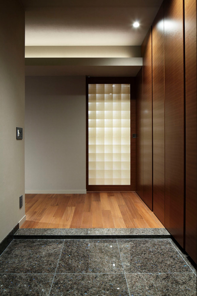 Imagen de hall gris minimalista de tamaño medio con paredes grises, suelo de granito, puerta simple, puerta marrón, suelo negro, papel pintado y papel pintado
