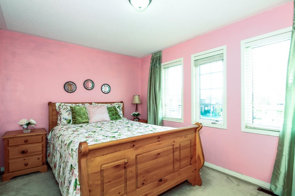 Photo of a mid-sized eclectic guest bedroom in Toronto with pink walls, carpet and no fireplace.