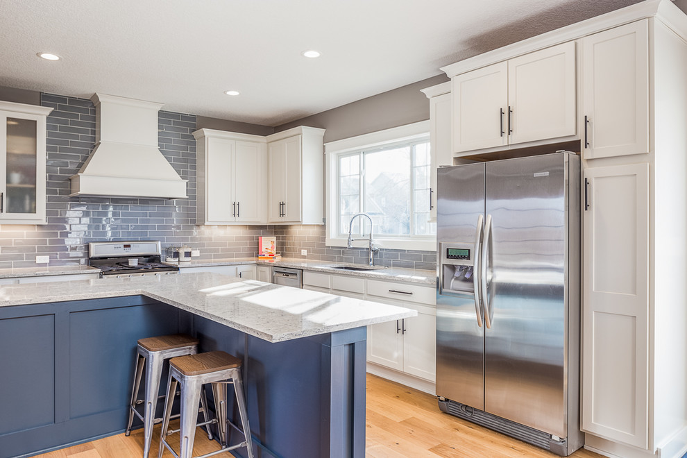 Inspiration for a large transitional l-shaped eat-in kitchen remodel with white cabinets, quartzite countertops, gray backsplash, glass tile backsplash, stainless steel appliances and an island