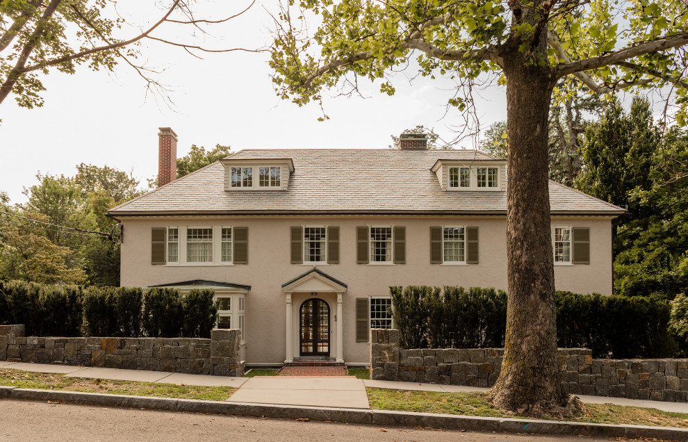 Traditional grey house exterior in Boston with a hip roof and a shingle roof.