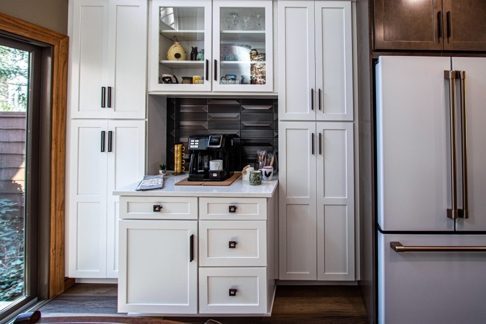 This is an example of a small traditional l-shaped kitchen pantry in Cleveland with a submerged sink, flat-panel cabinets, white cabinets, engineered stone countertops, brown splashback, ceramic splashback, white appliances, vinyl flooring, an island, brown floors and white worktops.