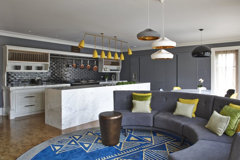 Expansive eclectic l-shaped open plan kitchen in Kent with an undermount sink, raised-panel cabinets, white cabinets, marble benchtops, black splashback, ceramic splashback, black appliances, medium hardwood floors and with island.